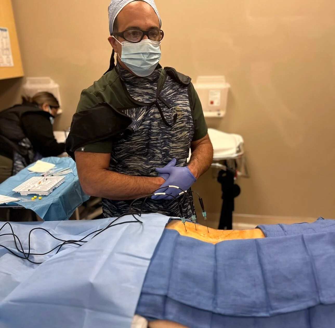 A doctor with folded arms standing next to a patient suffering from back pain.