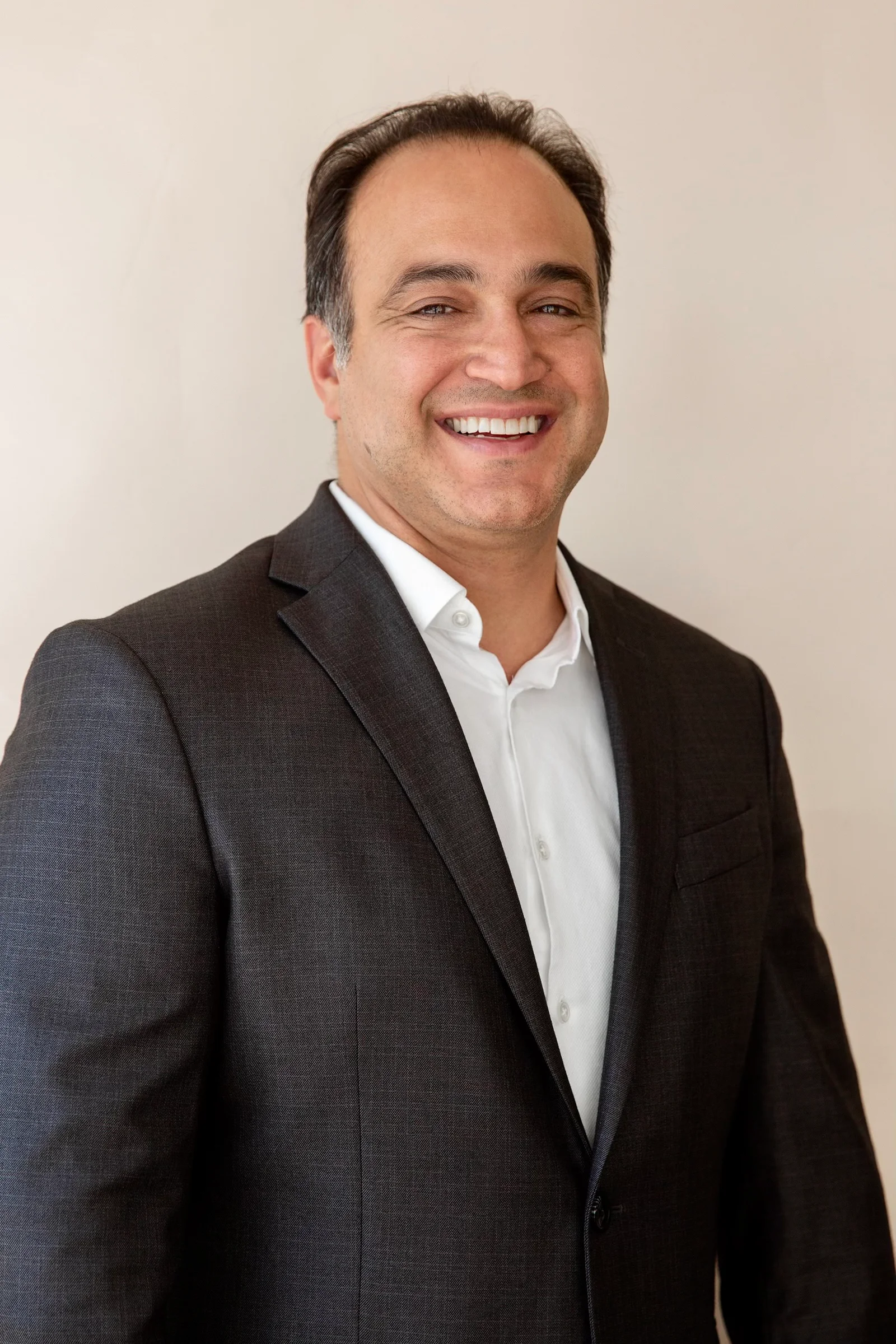 Dr. David Khandabi in a vertical portrait wearing a grey suit in Malaysian color tones.