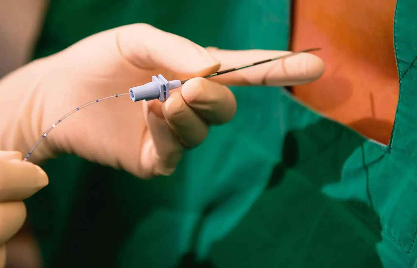 A hand holding a cannula needle near the back of a patient, prepared for spinal treatment.