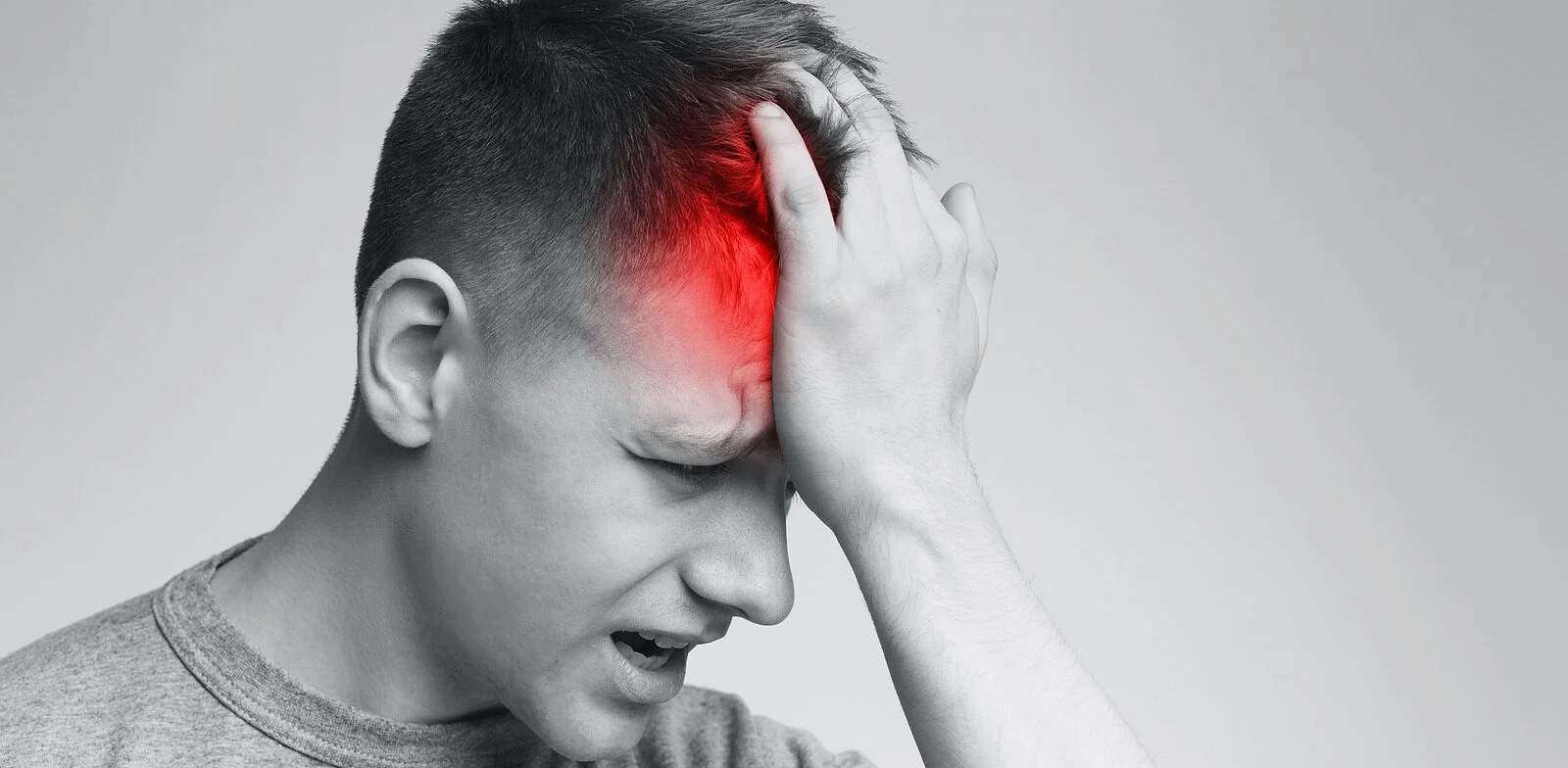 A black-and-white image of a person’s head with red spots highlighting areas of headache pain.