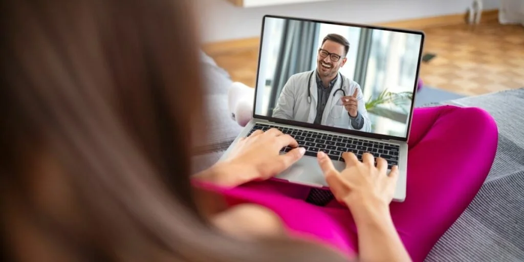 A male doctor conducting an online consultation with a female patient.