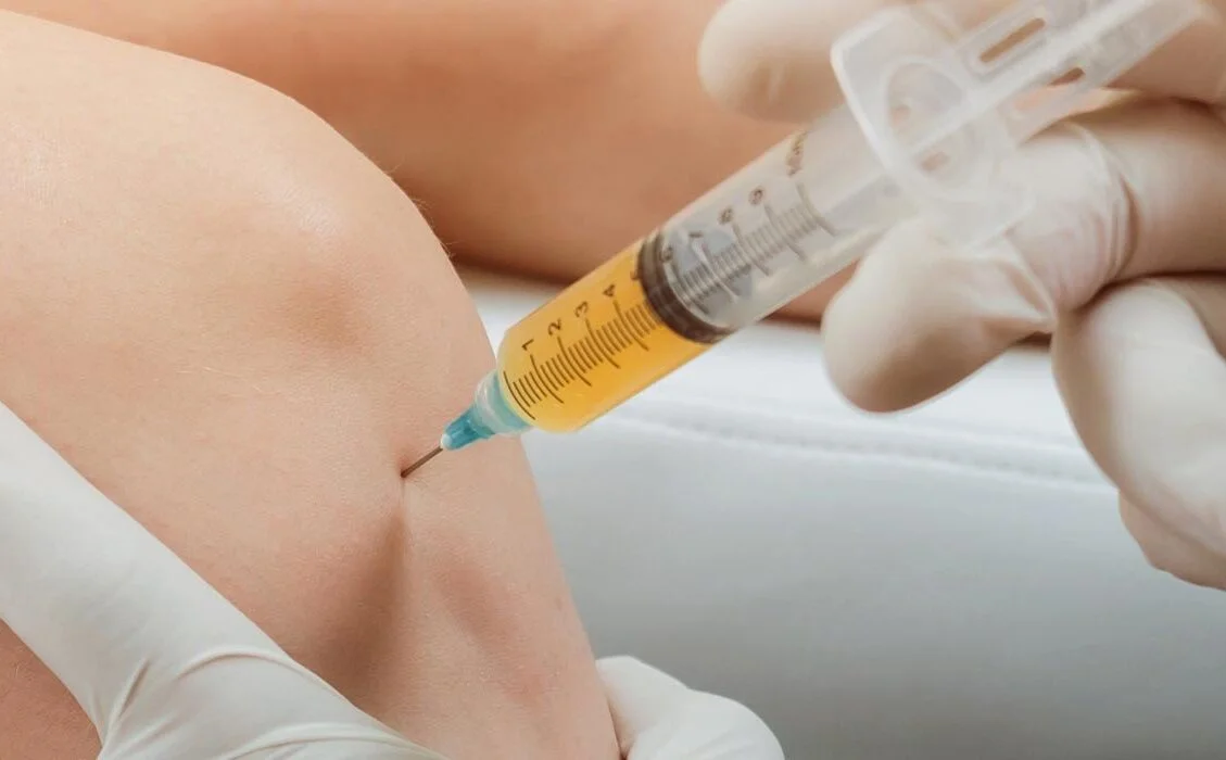 A medical professional administering an injection into a patient’s knee.